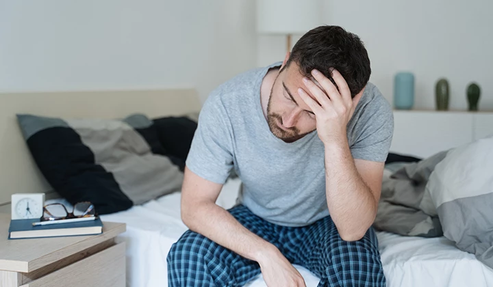 Mann sitzt erschöpft auf Bett Mann sitzt erschöpft auf Bett